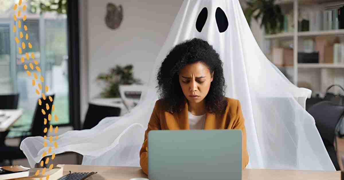A woman working on her laptop at a desk with a silhouette of a ghost behind her