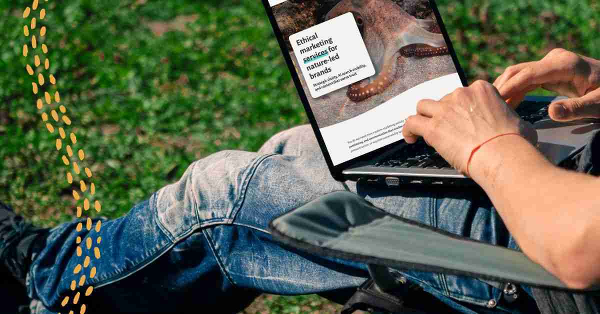 A man sitting outside in the sun on a green camping chair with boots on and a laptop in his lap looking at the Ethical Brand Marketing's services page