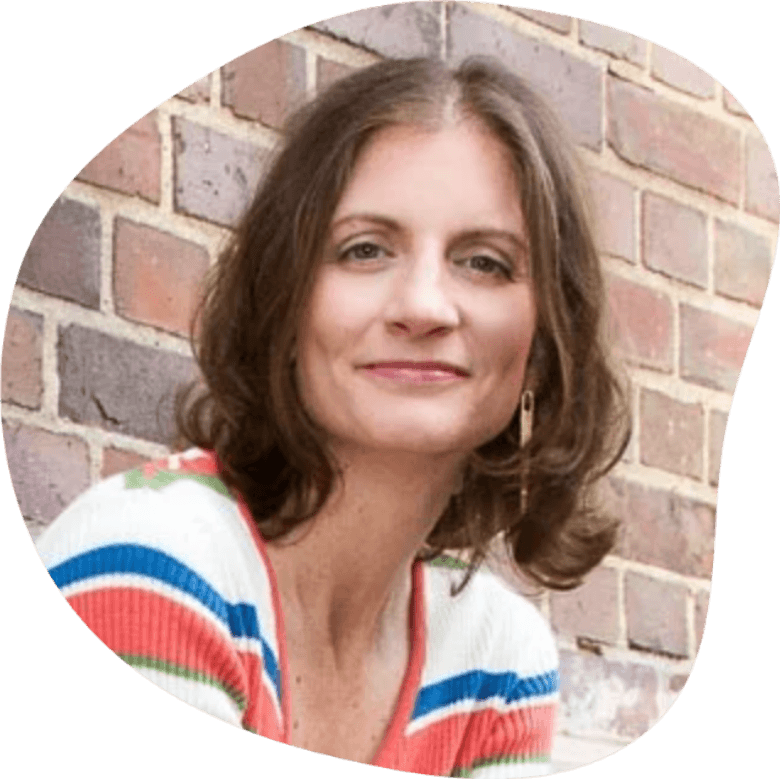 Headhsot of Jessica Lohmann wearing a striped dress sitting in front of a brick wall